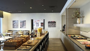 Un buffet de petit-déjeuner proposant une variété d’aliments et un espace repas avec des tables et des chaises.