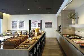 Un bufé de desayuno con diferentes opciones de comida y una zona de estar con mesas y sillas.