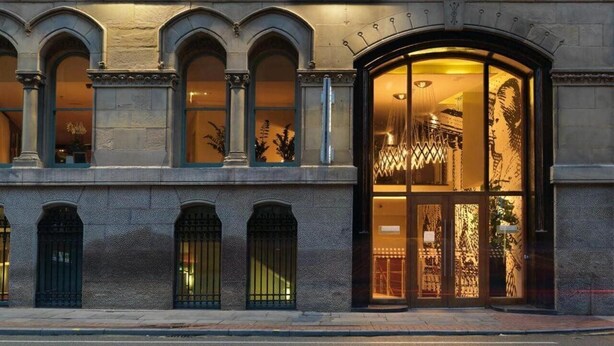 A building facade with arched windows and a large glass entrance. - Princess On Portland (Manchester)
