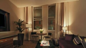 A cozy living room with a sofa, coffee table, and a dining area with chairs and a table. - Princess On Portland (Manchester)