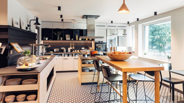 A modern kitchen with a dining area, large windows, and a patterned floor. - Harry's Home Berlin - Moabit Hotel & Apartments (Berlin)
