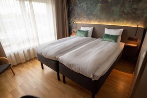Relax in a stylish room with a large bed, wooden floor, and large window.