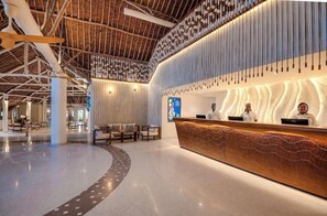 A modern reception area with a central desk, seating, and a high ceiling with exposed beams.