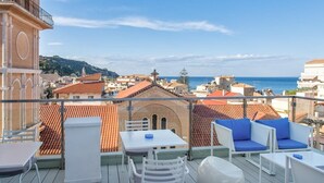 A balcony with white furniture and a clear view of the sea and cityscape. - Diana Hotel Zakynthos (Zakynthos)