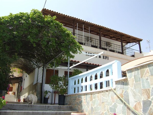 A building with a stone facade, a wooden balcony, and a staircase leading to the entrance. - Litsa Efi (Hersonissos)