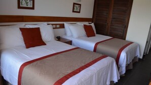 Two single beds with white and red bedding, wooden headboards, and a nightstand between them. - Peten Esplendido (Flores)