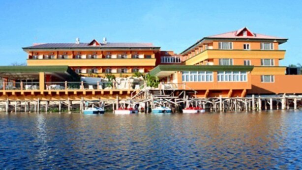 A multi-story hotel with a dock extending into the water, featuring several boats. - Peten Esplendido (Flores)