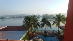 A pool area with palm trees and a view of a body of water. - Peten Esplendido (Flores)