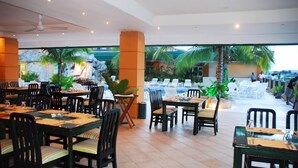 A restaurant with outdoor seating, tables, chairs, and a view of palm trees and a pool. - Peten Esplendido (Flores)