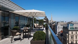 A rooftop terrace with a dining table, chairs, and an umbrella. - Hotel Sacher Wien (Vienna)