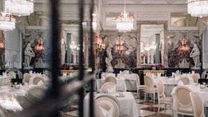 A formal dining room with multiple tables set for service, marble walls, and chandeliers. - Hotel Sacher Wien (Vienna)