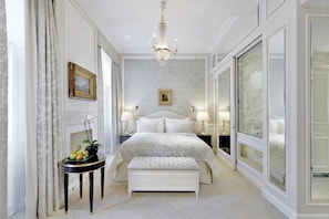 Relax in this elegant bedroom with a large bed, bedside tables, and a balcony offering a view of the outdoors.