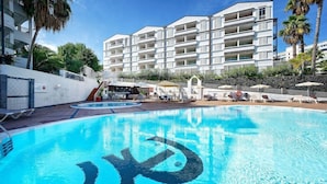 A swimming pool with a lifeguard tower, a covered seating area, and a building with balconies. - TC Apartamentos Dorotea (San Bartolomé de Tirajana)