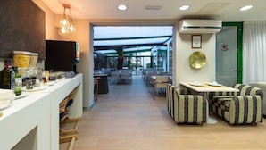 A modern hotel lobby with a reception desk, seating area, and a glass-enclosed dining space. - TC Apartamentos Dorotea (San Bartolomé de Tirajana)