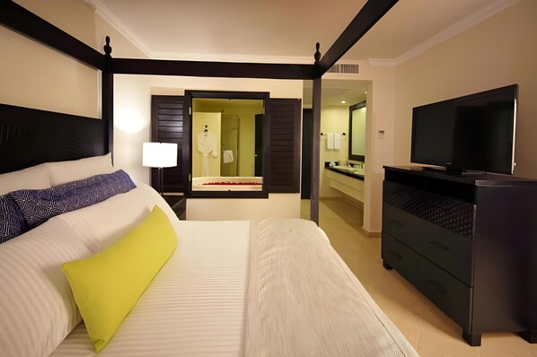 Ein Hotelzimmer mit Himmelbett, Fernseher, Kommode und Spiegel.