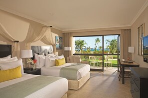 A hotel room with two beds, a desk, and a balcony with a view of palm trees and the ocean. - Dreams Playa Bonita Panama (Veracruz)