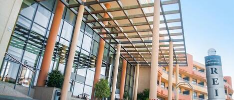A modern building with a glass facade, large columns, and a covered entrance area.