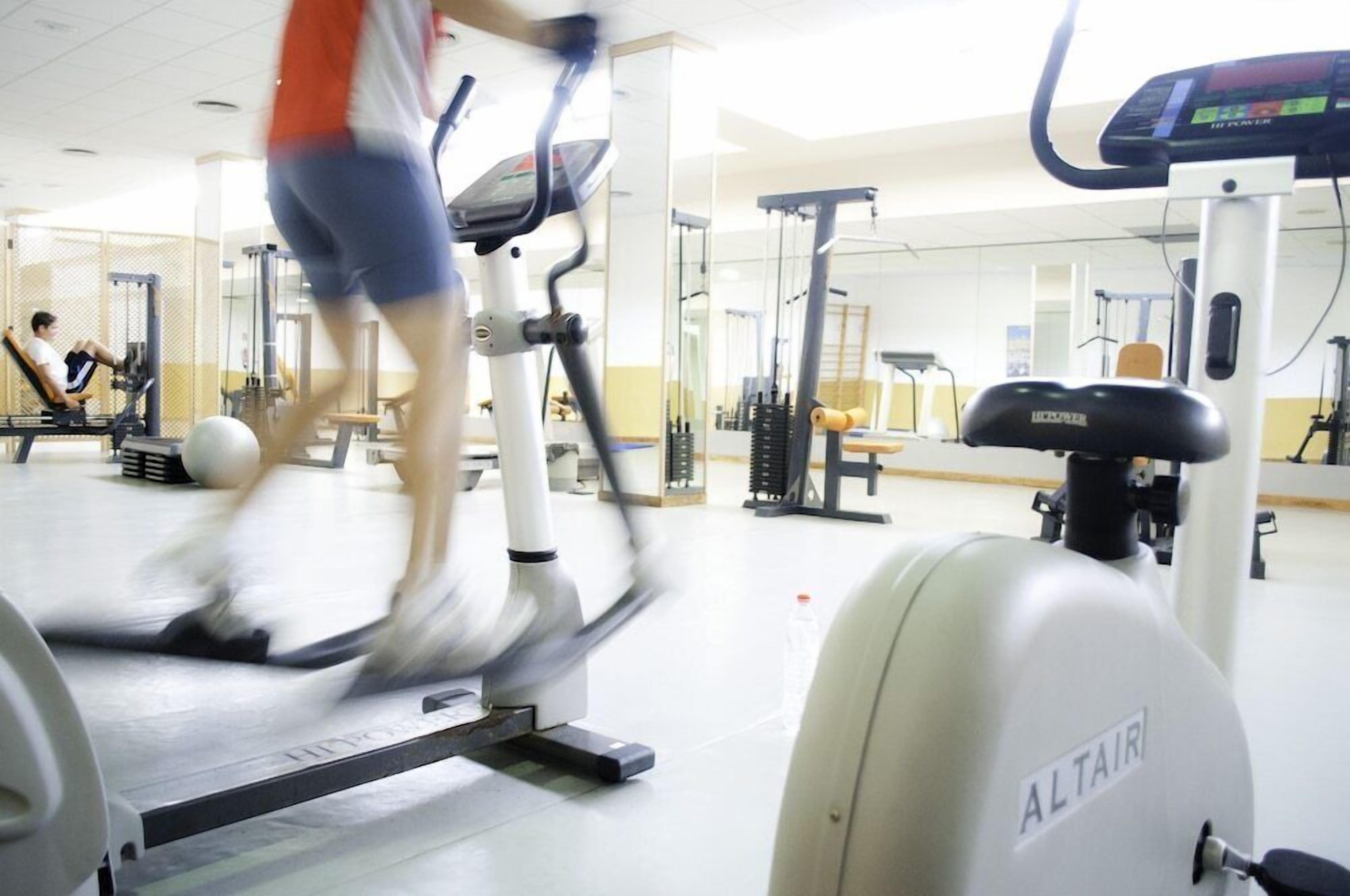 Un gimnasio con equipo de ejercicio, incluyendo una cinta de correr y una bicicleta estática.