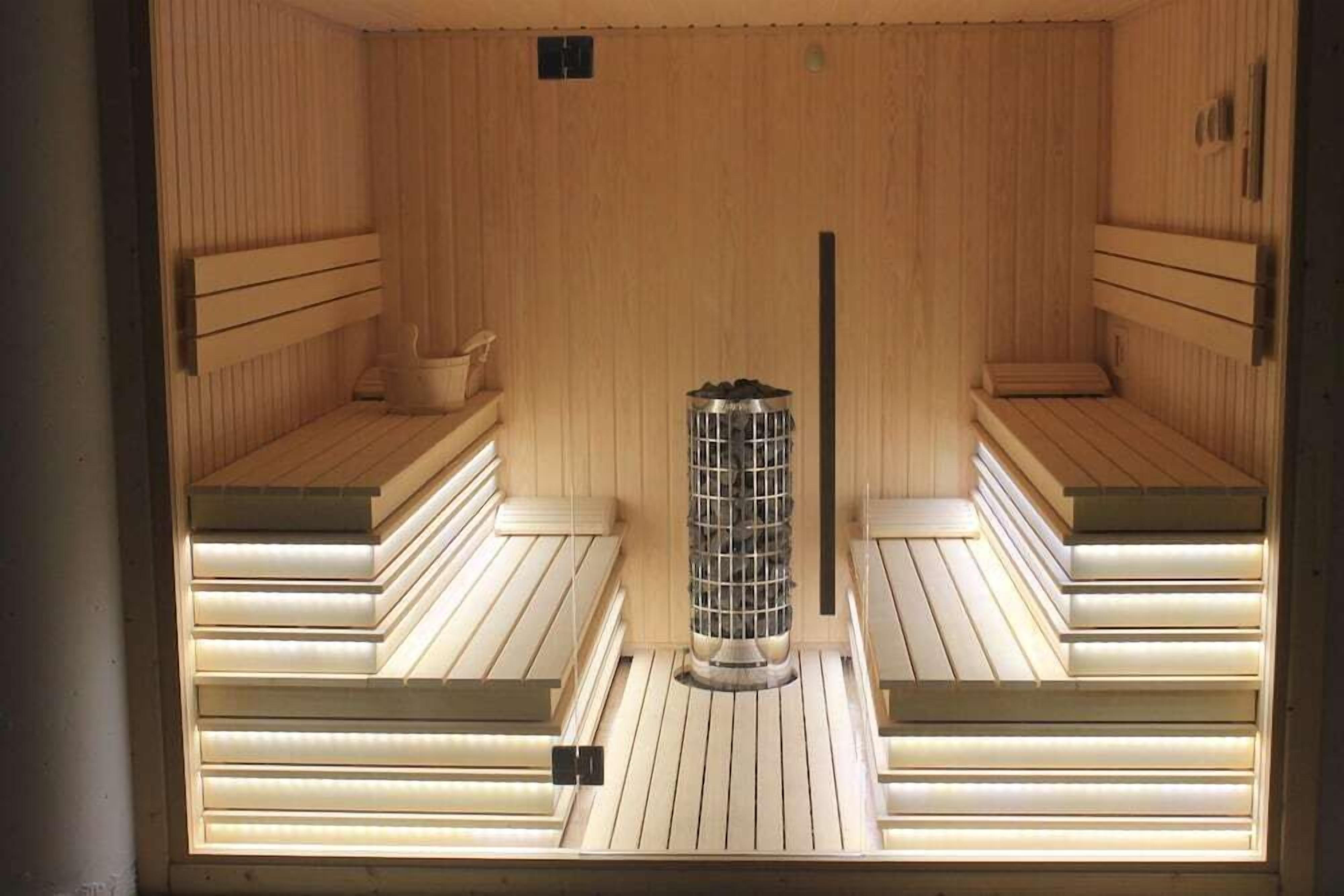 A sauna with wooden benches and a central heater.