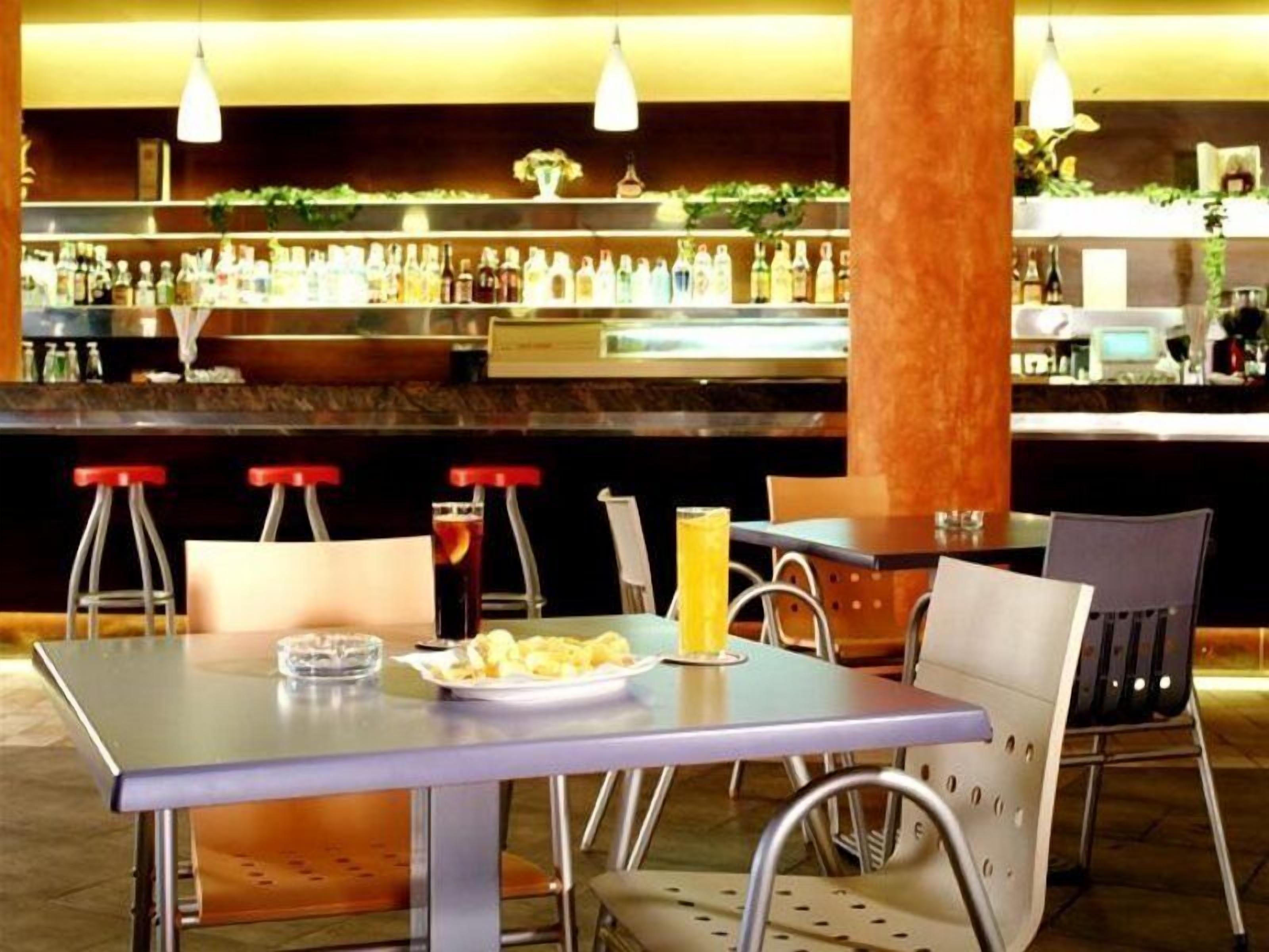 Un espace bar avec un comptoir, des tabourets et une table où sont servis des boissons et des en-cas.