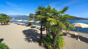 A beach with palm trees, sun loungers, and umbrellas. - Splendid (Baveno)