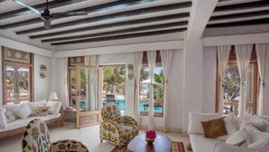 A spacious living room with a pool view, featuring a sofa, chairs, and a coffee table.
