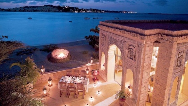 A seaside dining area with a fire pit, outdoor seating, and a view of the sea.