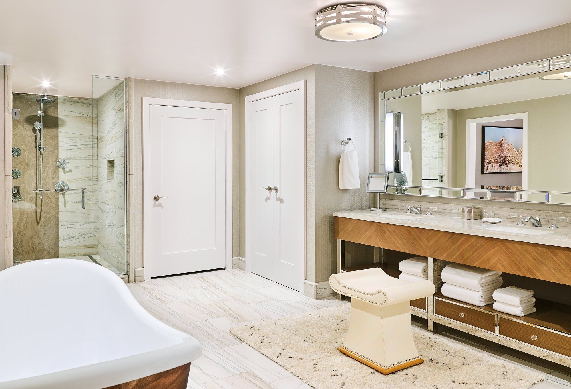 A modern bathroom with a freestanding bathtub, a large vanity with a mirror, and a shower area.