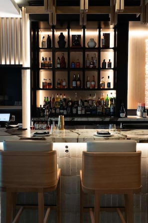 A bar area with wooden chairs, a marble countertop, and shelves of liquor bottles. - Grand Hyatt Vail Resort and Spa (Vail)