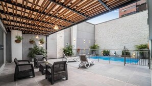 A covered outdoor area with wicker furniture, a pool, and potted plants. - Azor Hotel Cali Versalles Ex Vizcaya Real (Cali)