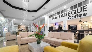 A modern interior with sofas, a coffee bar, and a sign for BAHAREQUE Coffee. - Azor Hotel Cali Versalles Ex Vizcaya Real (Cali)