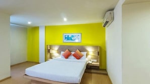 A hotel room with a bed, bedside tables, an air conditioning unit, and a framed picture on the wall. - Mapple Express Bangalore (Bengaluru)