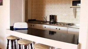 Une cuisine compacte équipée d’un plan de travail, d’une machine à café, d’un grille-pain et d’un four à micro-ondes.