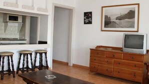 Une pièce avec une table en bois, un téléviseur posé sur une commode et un tableau encadré au mur.