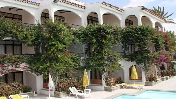 Un bâtiment blanc doté d’arcades et d’une piscine.