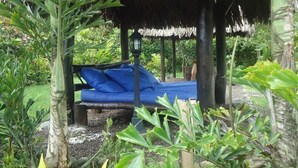A thatched-roof outdoor seating area with a blue cushion and a lantern. - Sumak Pakari Hosteria (Gualea)