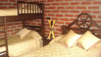 A room with two bunk beds, a wooden wheel, and a small table with a yellow lamp.