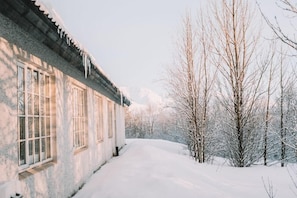 A snow-covered pathway leading to a building with large windows and a traditional architectural style. - Laxnes Hotel (Mosfellsbær)