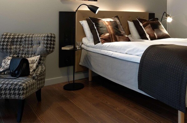 A neatly arranged hotel room with a bed, a chair, a floor lamp, and a bedside table. - Scandic Stavanger Forus (Stavanger)