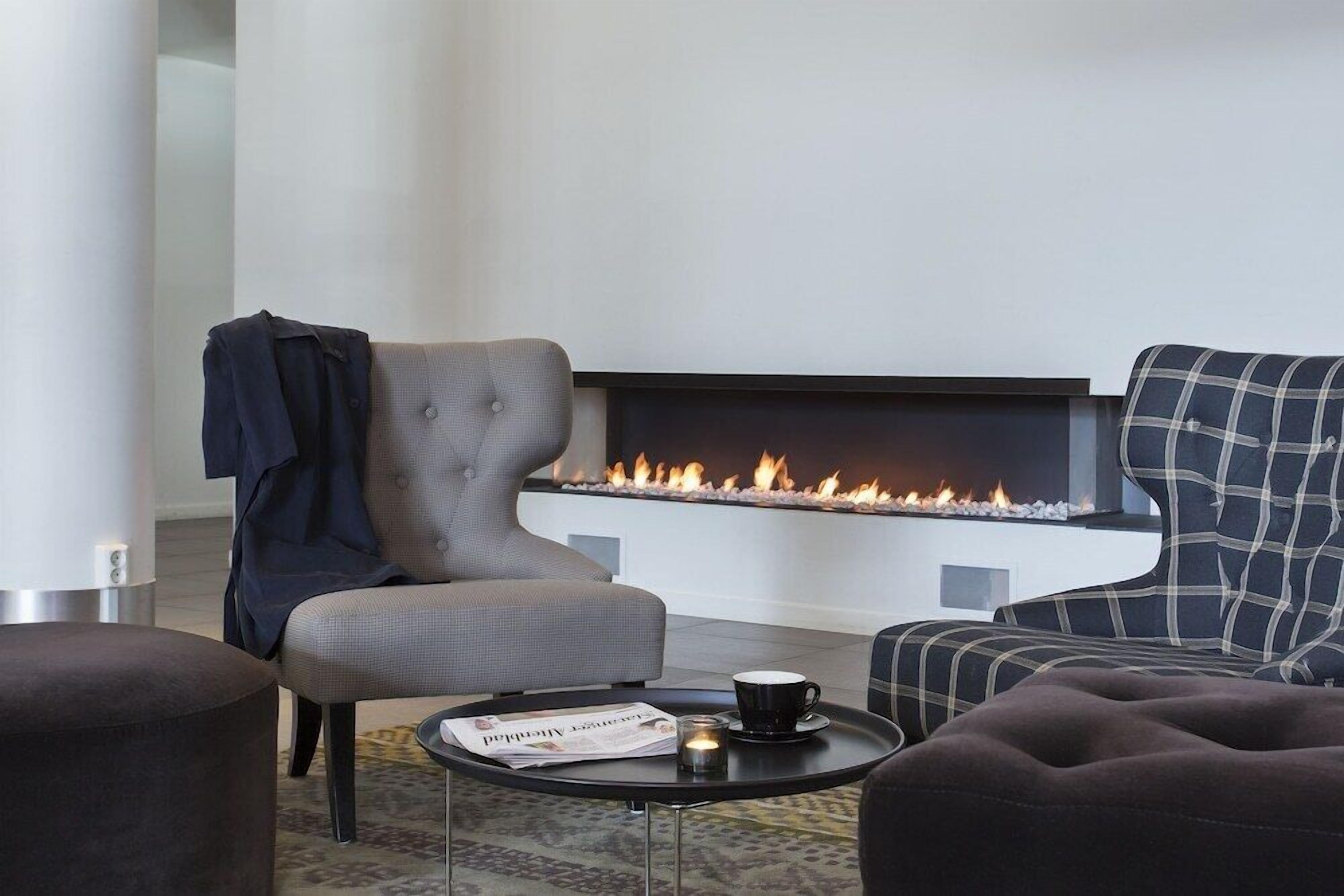 A modern living room with a fireplace, two sofas, a coffee table, and a magazine.