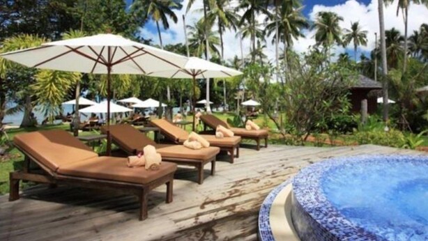 A poolside area with lounge chairs and umbrellas, surrounded by palm trees and a clear sky. - Gajapuri Resort Spa (Ko Chang)