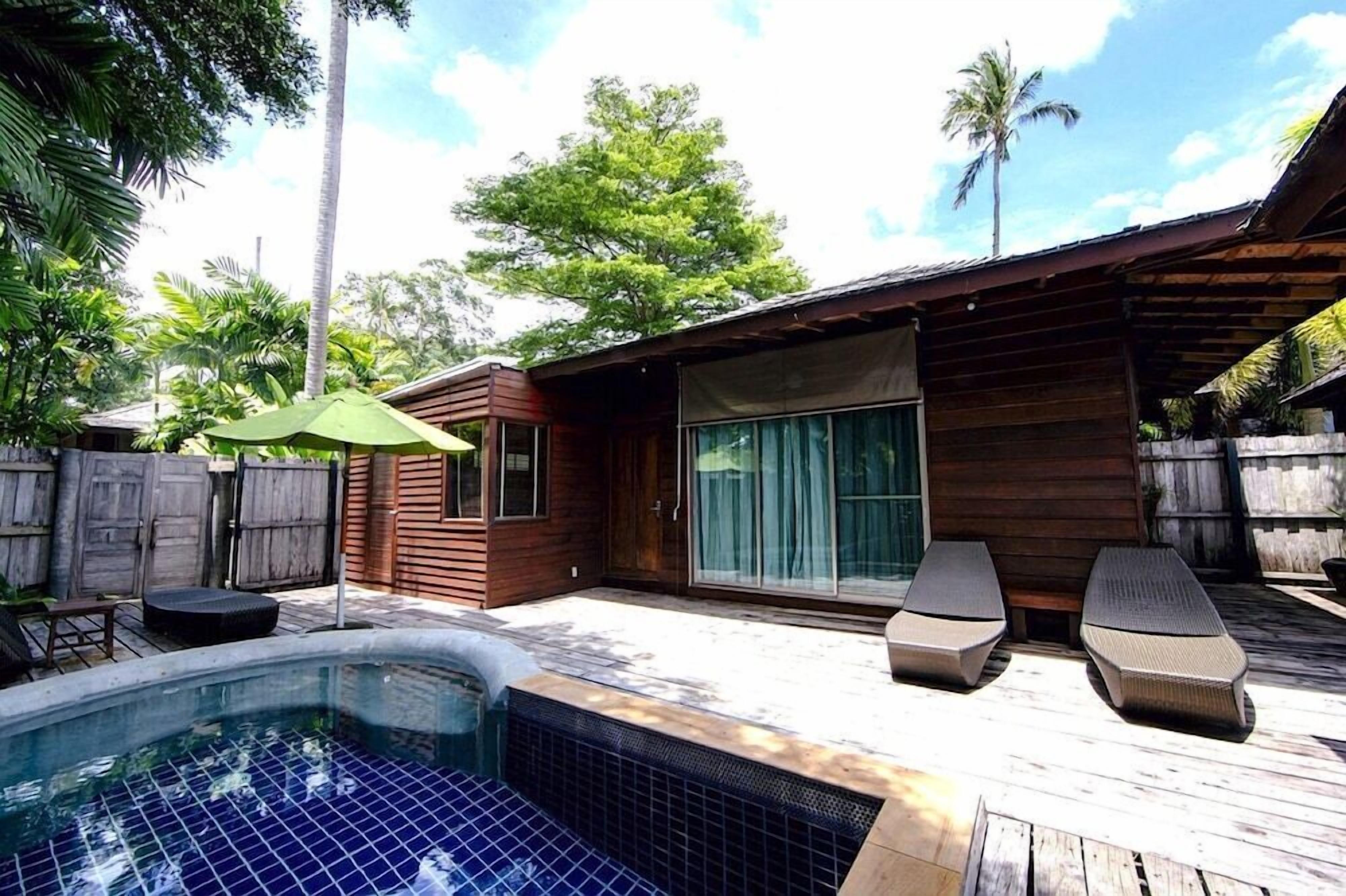 Ein Holzhaus mit Pool, Liegestühlen und einer überdachten Terrasse.