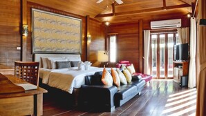 A wooden cabin room with a bed, a sofa, a TV, and a ceiling fan. - Gajapuri Resort Spa (Ko Chang)