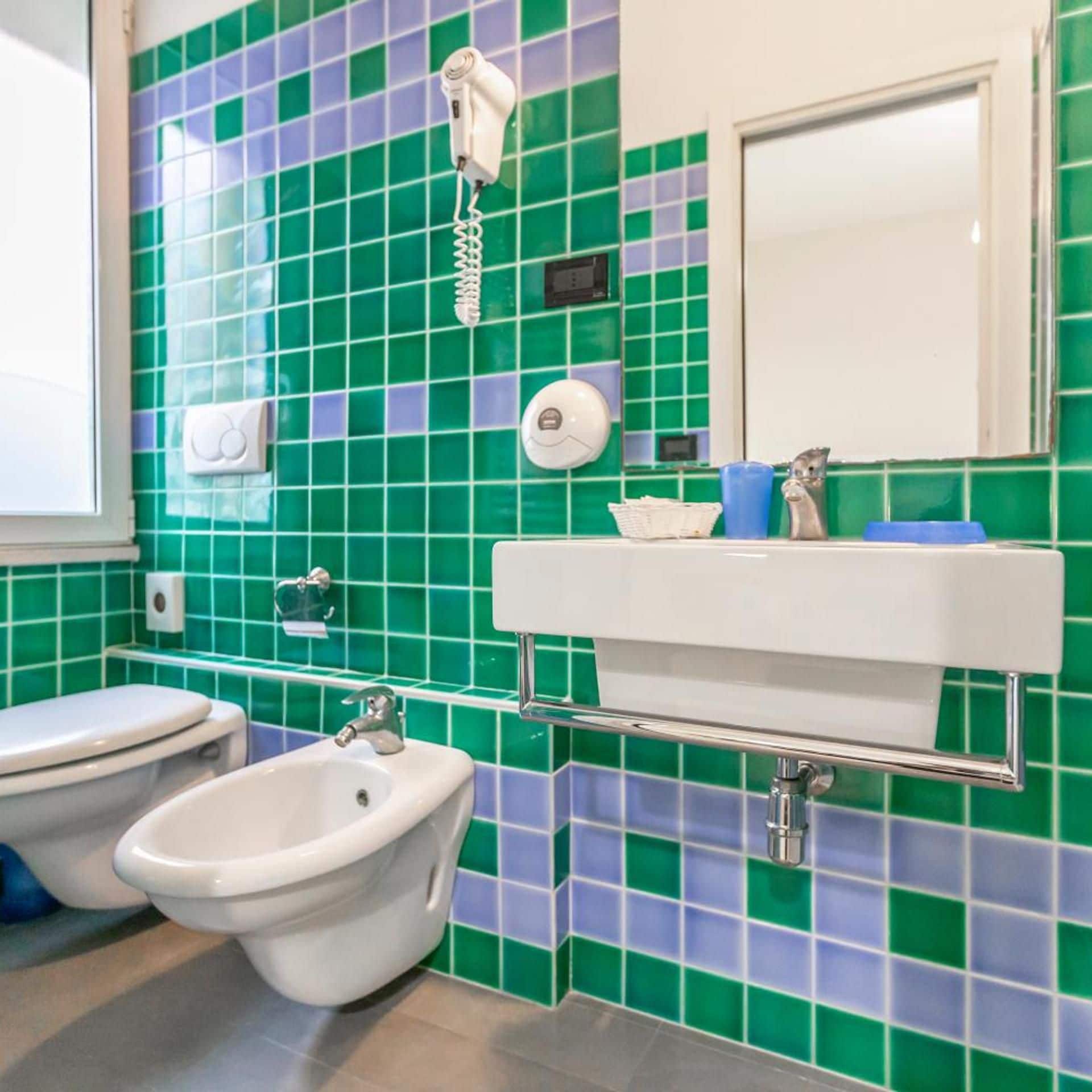 A bathroom with a toilet, bidet, and sink.