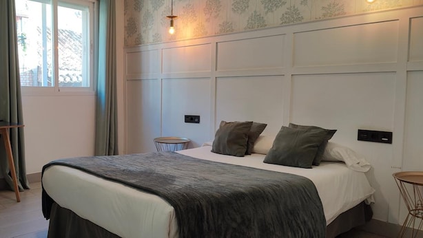 Un dormitorio con cama, mesitas de noche, escritorio y silla.