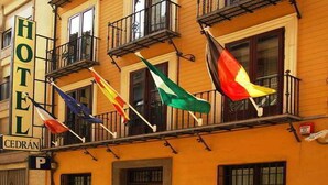 Un hotel con varios balcones, un letrero que indica un estacionamiento y varias banderas.