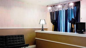 Un área de recepción con un sofá de cuero negro, un mostrador de recepción, una lámpara y un monitor de computadora.