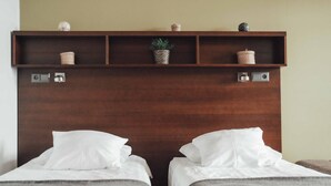 Une chambre d’hôtel avec deux lits, une tête de lit en bois et une étagère ornée d’objets décoratifs.