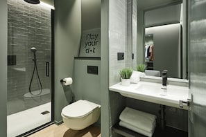 Un baño moderno con cabina de ducha de vidrio, un inodoro, un lavabo con espejo y un perchero para toallas.