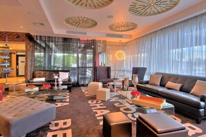 A modern living room with a black leather sofa, a glass coffee table, and a patterned rug. - Tryp San Jose Sabana (San José)